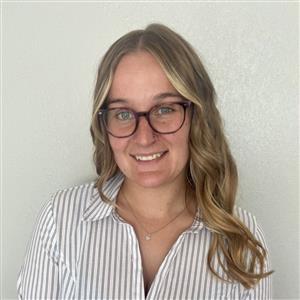 picture of woman with glasses on, blonde curled hair, and a striped button up blouse